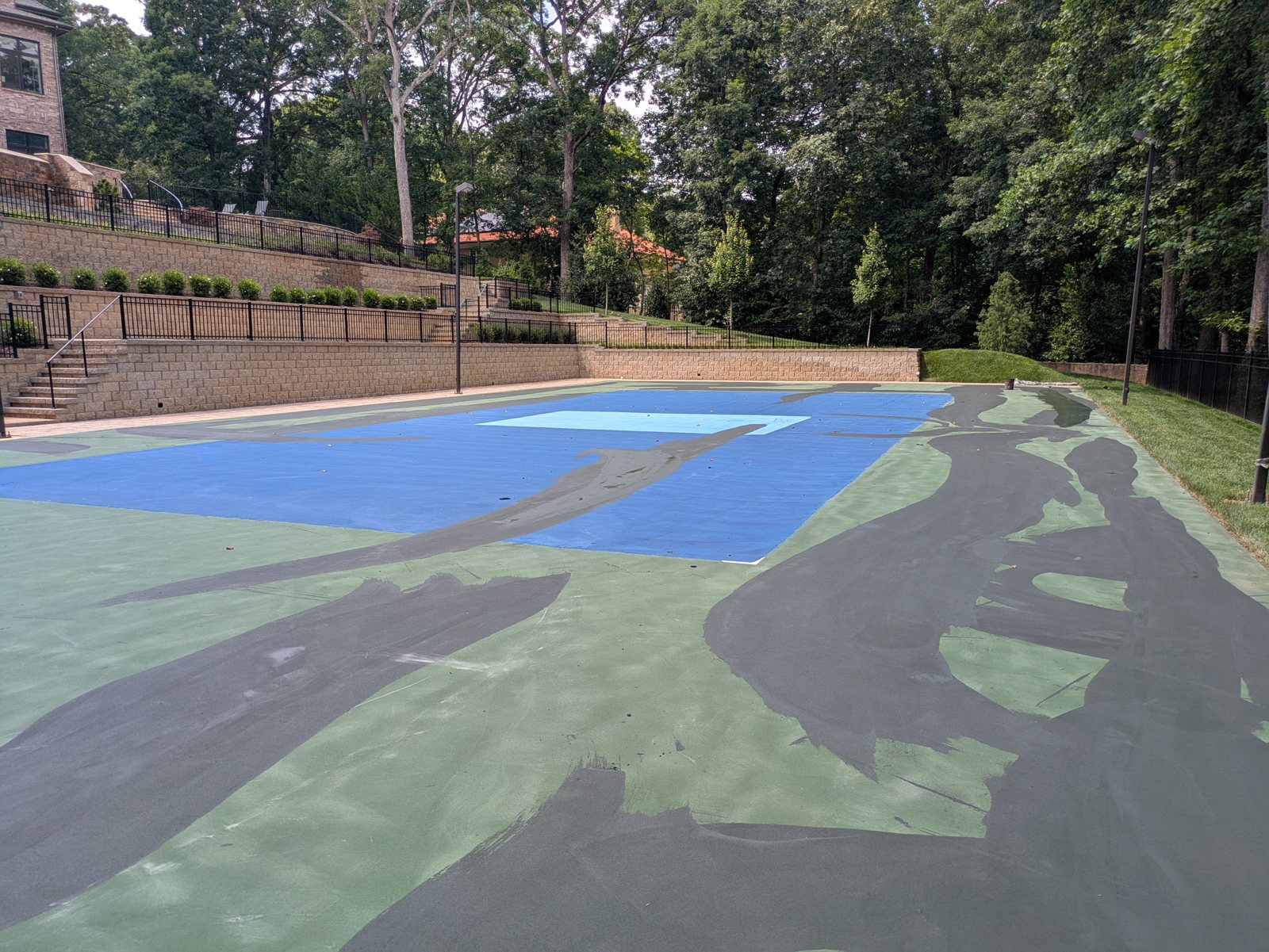 Fresh color coat going down on a resurfaced court